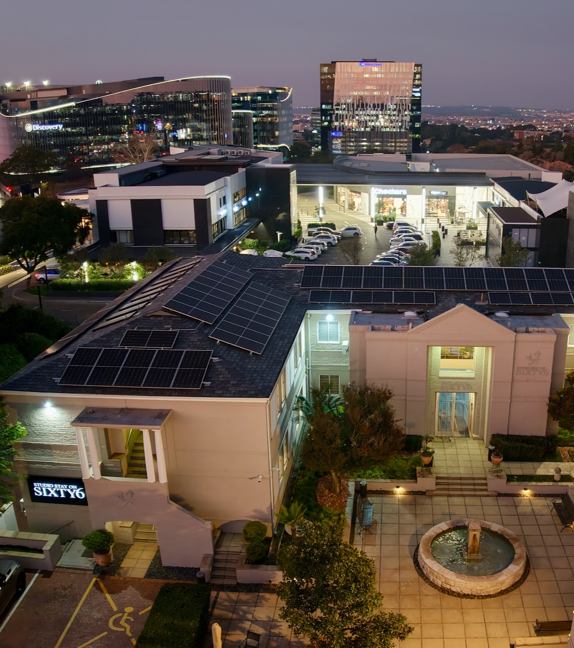 Studio Stay on Sixty6 courtyard fountain at dusk with Block A and the Sixty6 entrance